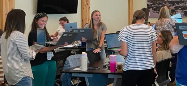Educators working together in a session, standing with laptops and talking