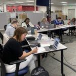 JCPS educators working in a small group coaching session, sitting at tables with laptops open