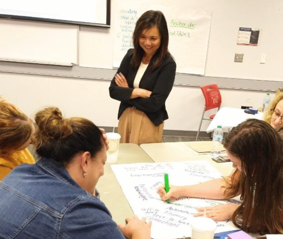 Consultant Myla Lee, observing REMC educators working at a table