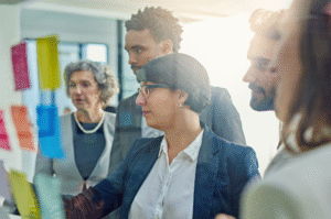 Business people looking at colorful sticky notes on a glass wall.