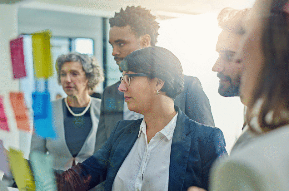 Business people looking at colorful sticky notes on a glass wall.