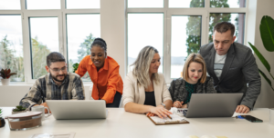 Group of professionals at a table talking and looking at laptops